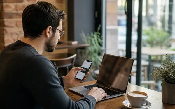 Foto generada por IA de un desarrollador revisando una app en portátil y móvil