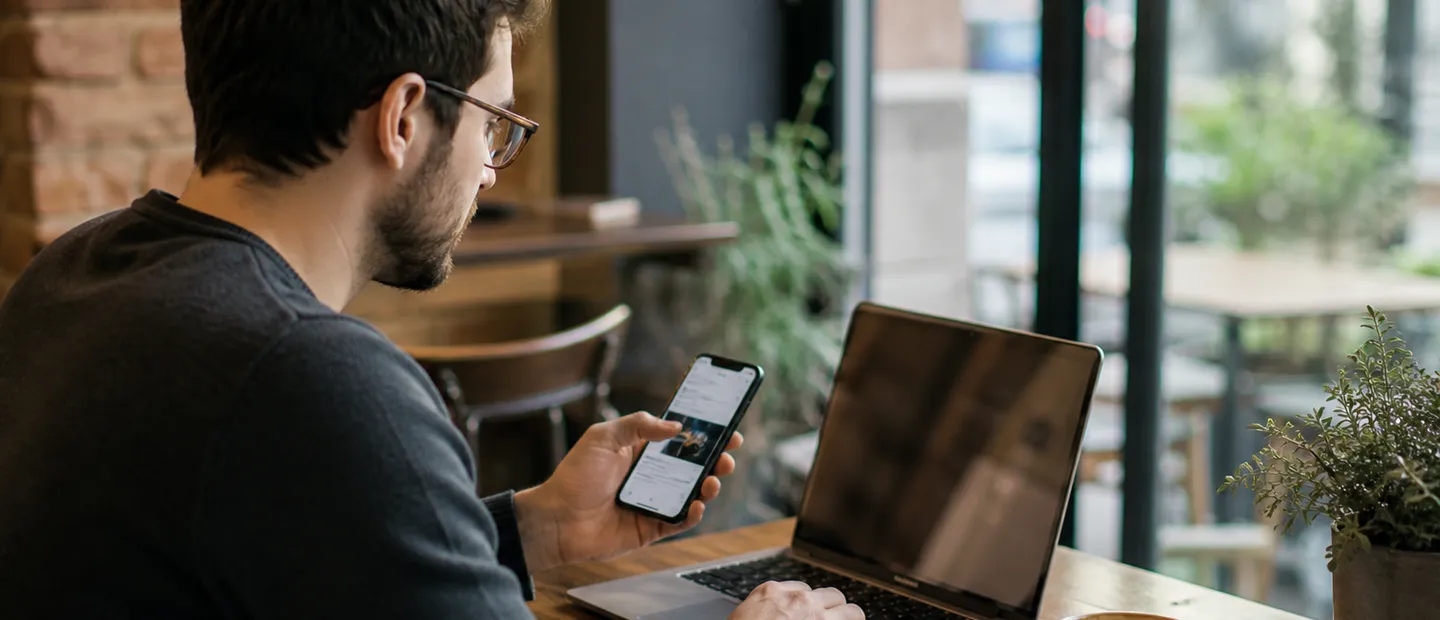 Foto generada por IA de un desarrollador revisando una app en portátil y móvil