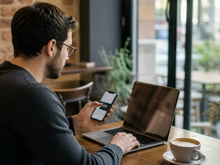 Foto generada por IA de un desarrollador revisando una app en portátil y móvil